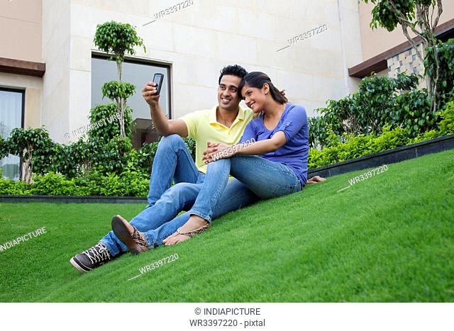 Couple taking a self portrait on a lawn