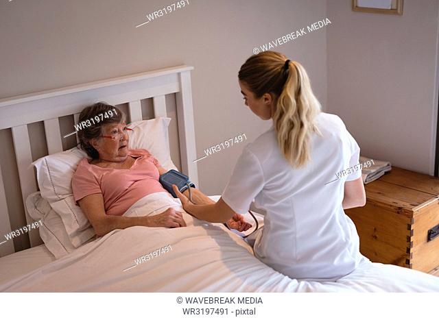 Physiotherapist checking blood pressure of senior woman