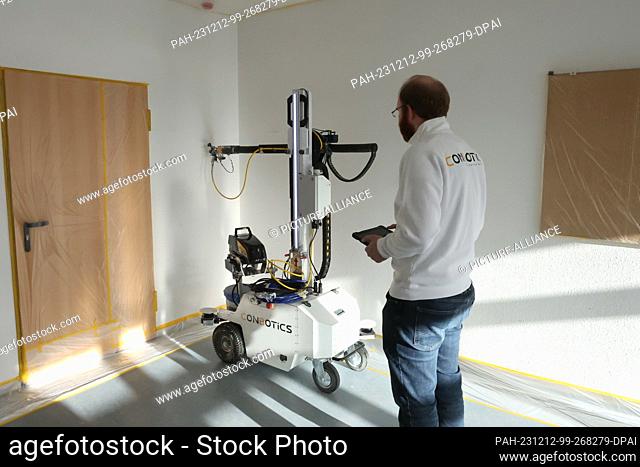12 December 2023, Thuringia, Erfurt: Vincent Werner from Conbotics works on a painting robot at the launch event of the Competence Center for Robotics and...