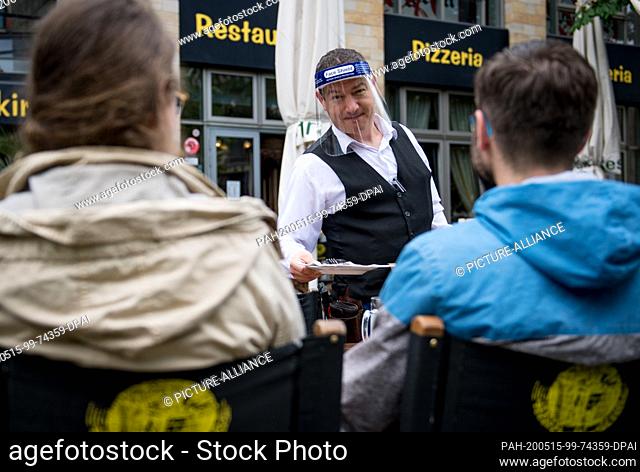 15 May 2020, Saxony, Leipzig: A waiter serves guests in the ""Brauhaus an der Thomaskirche"". After an eight-week break, many pubs and restaurants in Saxony...