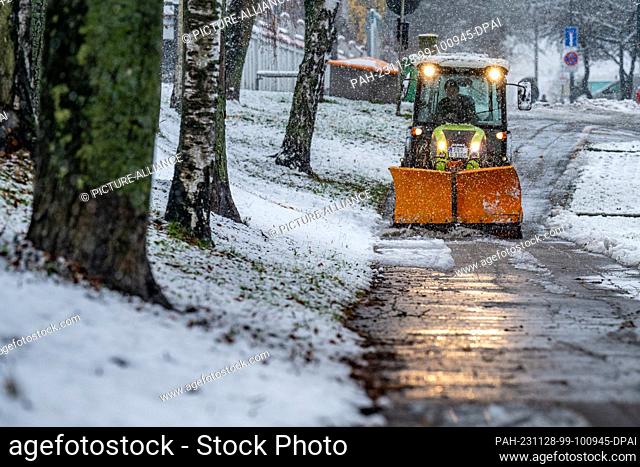 28 November 2023, Bavaria, Straubing: A city clearing vehicle removes snow from a path. The German Weather Service is expecting more fresh snow