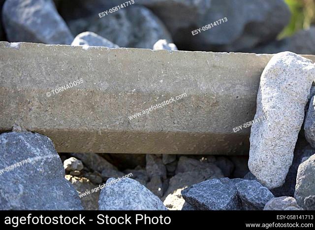 Cement bumper torn from the ground and stacked on a pile of granite rocks