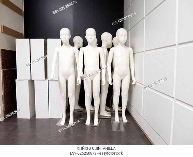 group of white plastic fashion shop mannequin of child or boy naked without clothes stand up stored huddled in corner of industrial warehouse shop