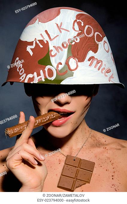 Beautiful woman with chocolate cigar in hand and helmet
