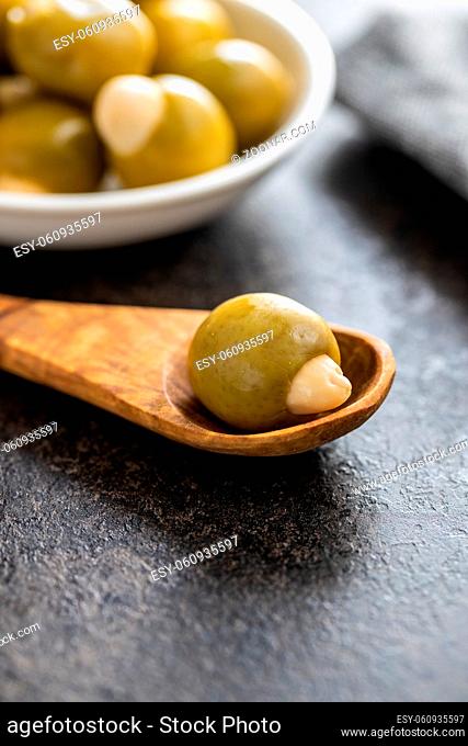 Pitted green olive stuffed with almonds on wooden spoon
