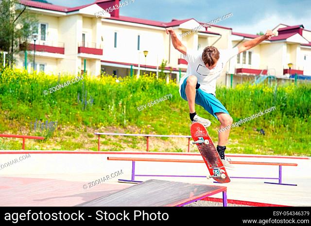 Boy skateboarder in a skate park doing an ollie trick on a skateboard against a sky and thunderclouds