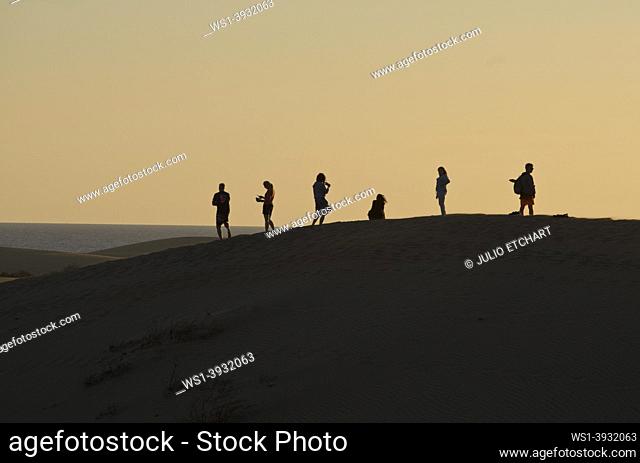 People watching the sunset at and taking selfie photos at Maspalomas sand dunes, near Playa de los Ingleses, Gran Canaria, Spain