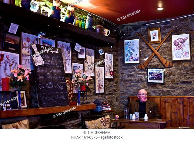 Elderly man sits alone with cup of tea and beer in traditional Irish Bar Grainne's in Timoleague, West Cork, Ireland