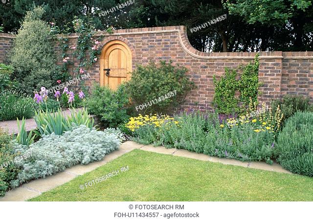 Lawn and herbaceous border in walled country garden in summer