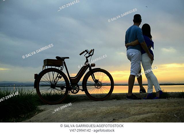 A wedding couple arrives by bicycle to the Albufera Natural Park to see the sun gate