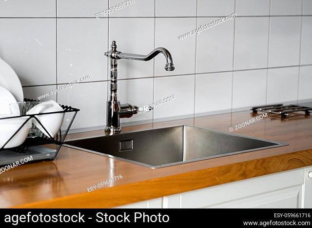 Kitchen sink and faucet. Stainless kitchen sink and tap water. The interior of the modern kitchen room in the loft apartment. Built-In Appliances