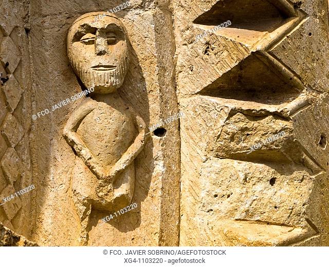 Escultura de ejecución rudimentaria representando una figura humana en una de las arquivoltas de la portada de estilo románico de la iglesia de San Pedro -...