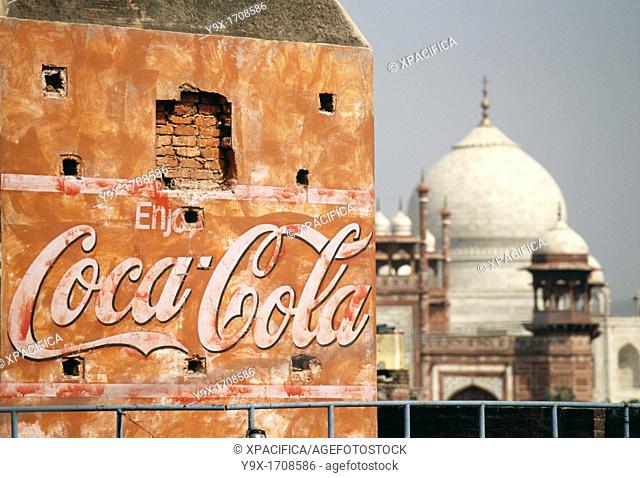 A Coca Cola billboard on an old and worn building with the Taj Mahal in the background The Taj Mahal is one of the most famous landmarks in India and around the...