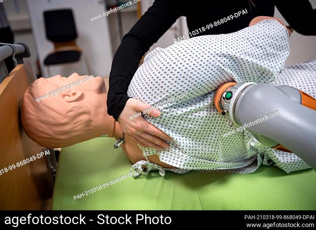 02 March 2021, Lower Saxony, Oldenburg: Robotic arms assist Anna Brinkmann, research assistant, in moving a doll during an experimental setup at Carl von...