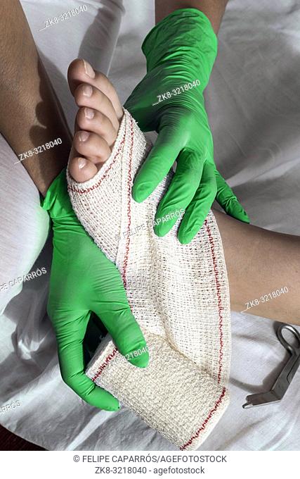 Close-up Of A Nurse Tying Bandage On Patient's Foot