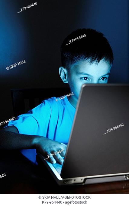 Young Asian boy using laptop at night