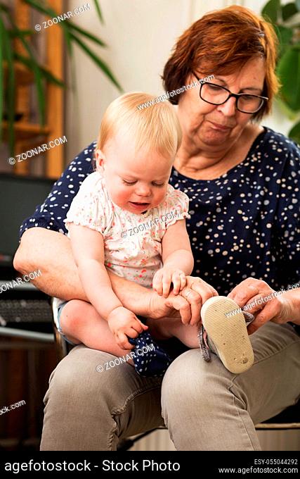 Grandmother and grand daughter, puts on a shoe on her lap, Family portrait