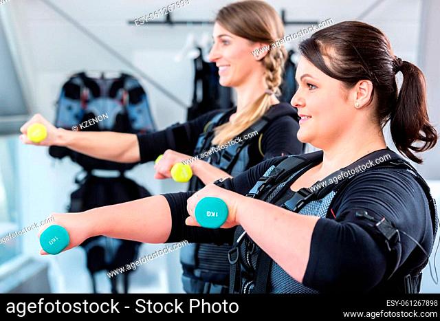 Two women friends exercising together for fitness in wireless ems center