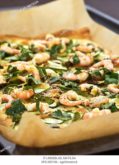 Pizza topped with prawns, vegetables & herbs on baking tray
