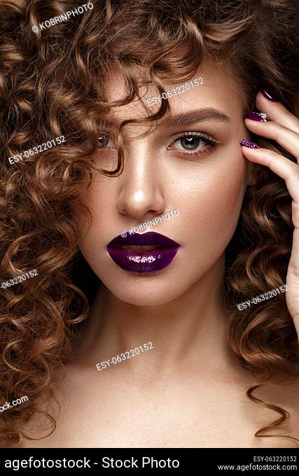 Beautiful girl with evening make-up, purple lips, curls and design manicure nails. beauty face. Photos shot in studio