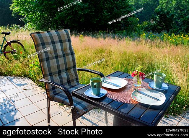Breakfast on the terrace in front of green nature, with a bike on a beautiful summer day