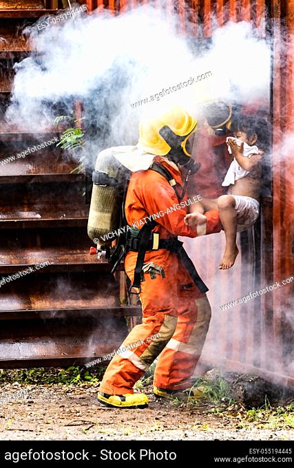 Firefighter rescue girl little child from burning building. He hold the girl and rescue her through window of building. Firefighter safety rescue from accident...