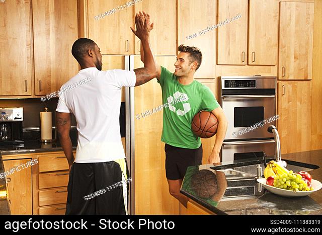 Men high fiving in kitchen