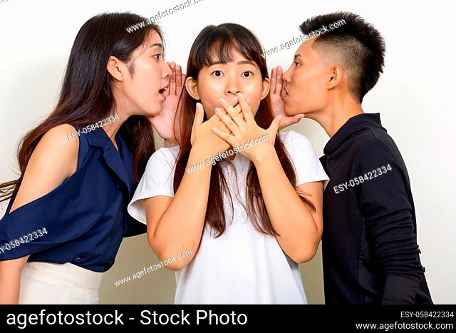 Studio shot of three young beautiful Asian women as friends together against white background