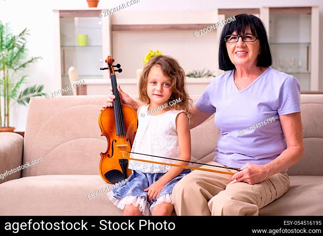 The old lady teaching little girl to play violin