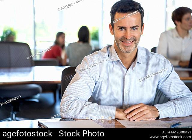 Portrait of mature man sitting at desk in office
