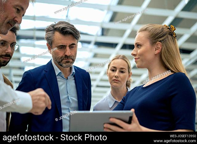Businesswoman discussing with colleagues over tablet PC