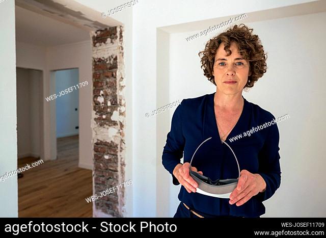 Mature saleswoman with virtual reality simulator standing in new home
