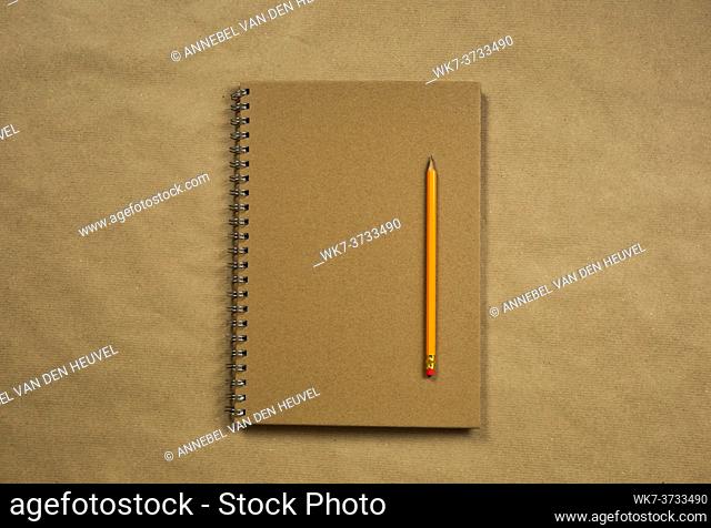 Brown notebook and classic pencil on brown plain paper background texture, copy space or space for text, business or education concept top view modern retro...