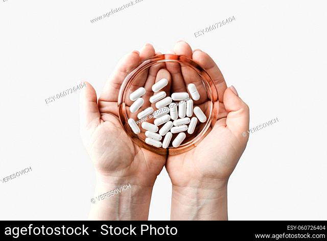 Pills on glass saucer in female hands. Pharmaceutical medicaments