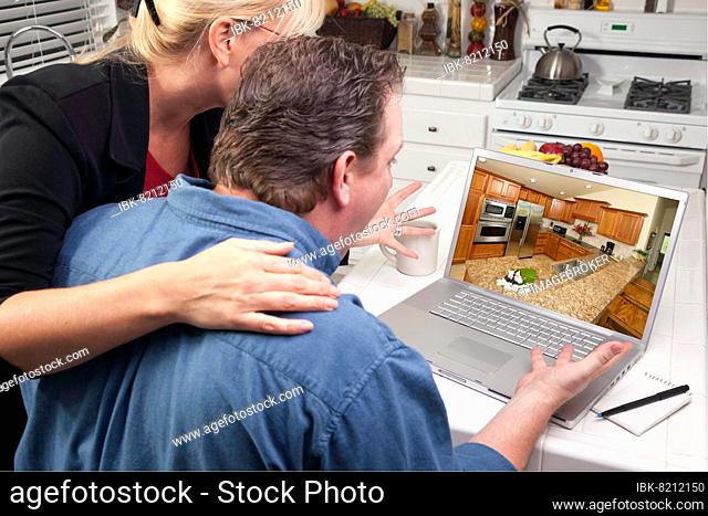 Couple in kitchen using laptop to research home improvement ideas. screen can be easily used for your own message or picture