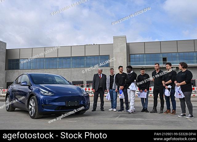 01 September 2021, Brandenburg, Grünheide: Jörg Steinbach (SPD, l), Minister of Economics of Brandenburg, stands next to a Tesla Model Y and the first trainees...