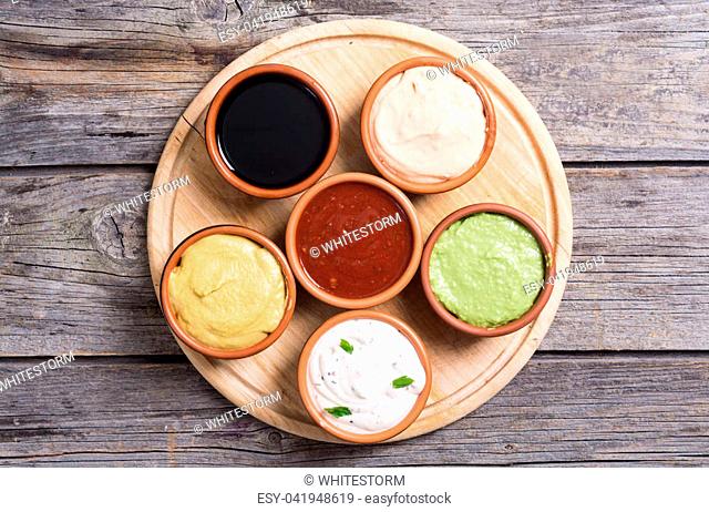 Set of sauces in bowl on wooden background