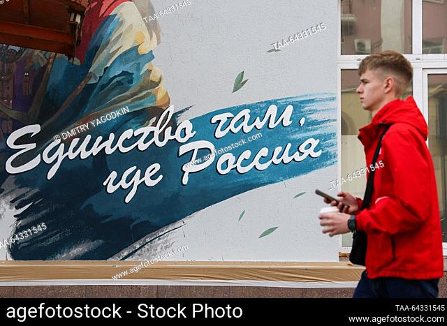 RUSSIA, DONETSK - 3 de noviembre de 2023: Un hombre pasa por un graffiti pintado por el artista Vladislav Stepnoi en un muro de construcción para conmemorar el...