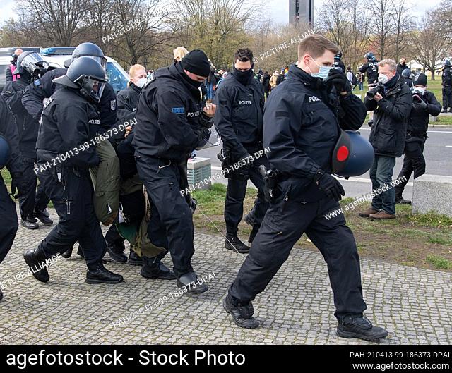 13 April 2021, Berlin: Police officers lead away a demonstrator in the government quarter who was protesting against the tightening of the infection protection...