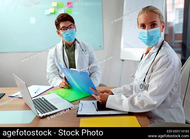 Portrait of diverse male and female doctor wearing face masks meeting in hospital office