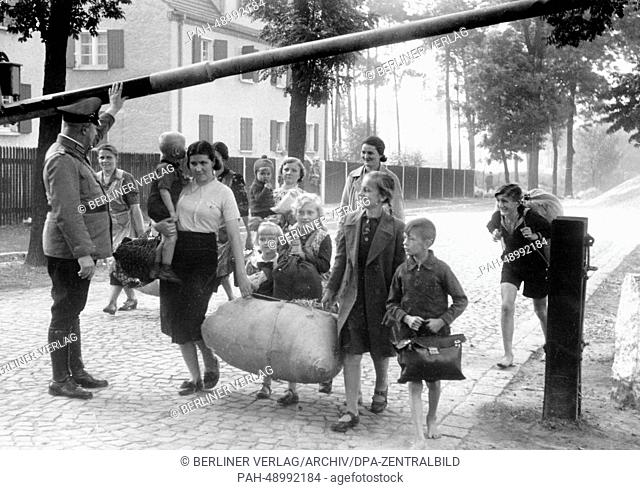 The picture from a Nazi news report shows German refugees from Poland crossing the border in August 1939. The original Nazi propaganda text on the back of the...