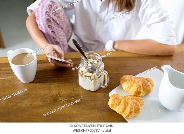 Woman at breakfast table using cell phone