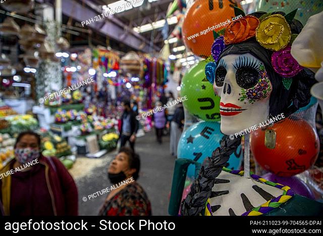 19 October 2021, Mexico, Mexiko-Stadt: A doll of the traditional ""Catrina"" stands in front of Reyna Garcia's stand at the popular ""Jamaica"" market before...