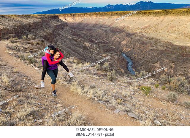 Hispanic woman carrying friend on her back in remote area