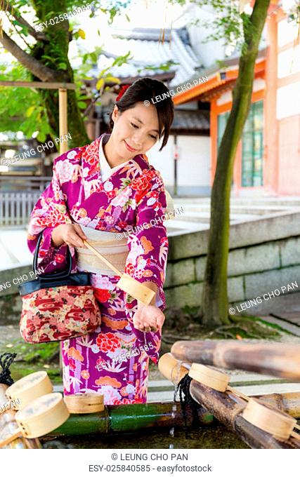 Young japanese woman use of the bamboo ladle in water fountain