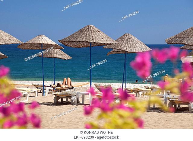 Woman sunbathing beneath a sunshade on a sandy beach, Cirali, Mediterranean Sea, Lycia, Turkey, Asia