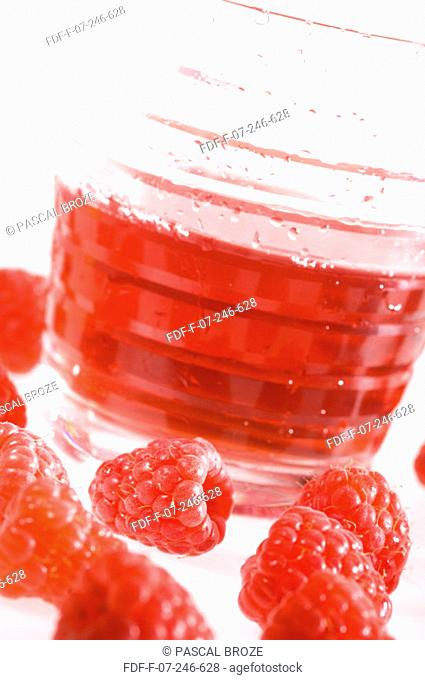 Close-up of a glass of raspberry juice and raspberries