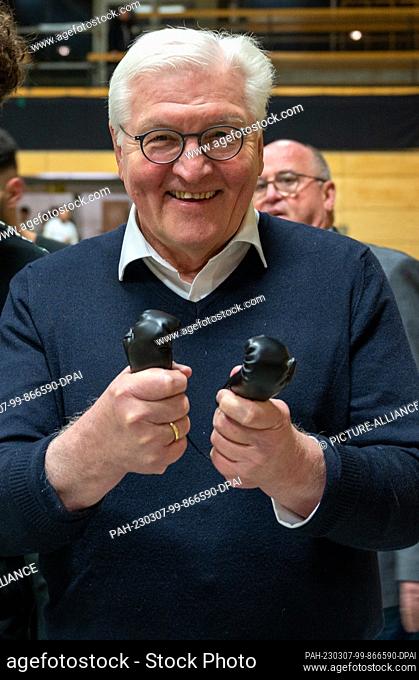 07 March 2023, Saarland, Völklingen: Federal President Frank-Walter Steinmeier holds a pair of mini boxing gloves that he was given during a visit to Boxclub 82...