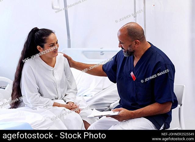 Female patient on hospital bed talking to nurse