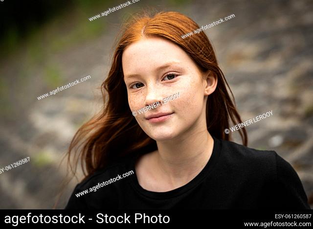 Red haired twelve year old girl with freckles posing with a city bokeh background, Jette, Belgium
